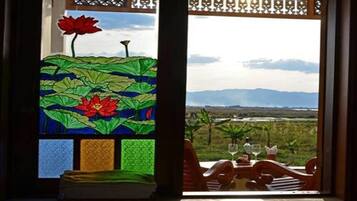 A dining area with a table set for two, overlooking a landscape with mountains.