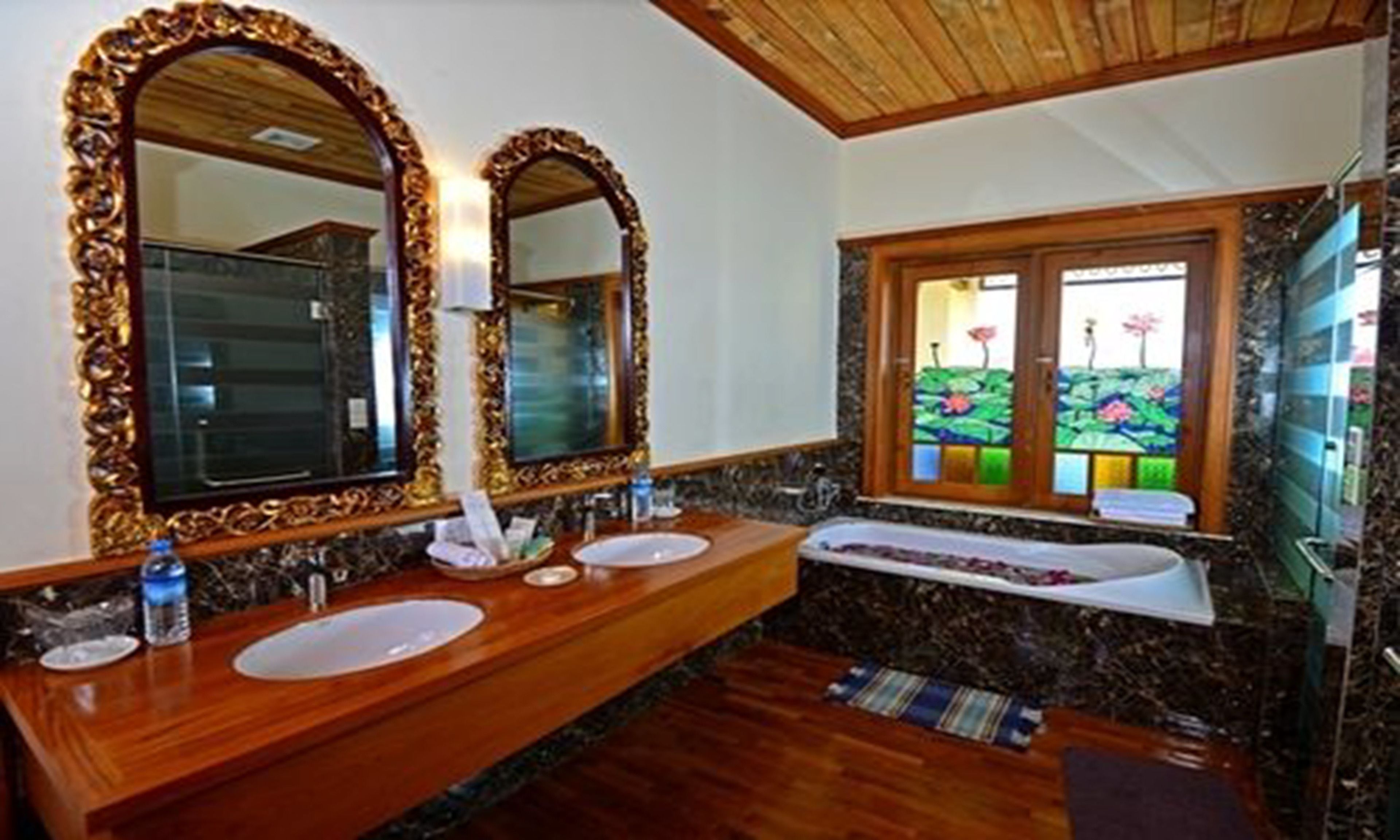 Een badkamer met twee wastafels, een grote spiegel en een raam met uitzicht op bloemen.