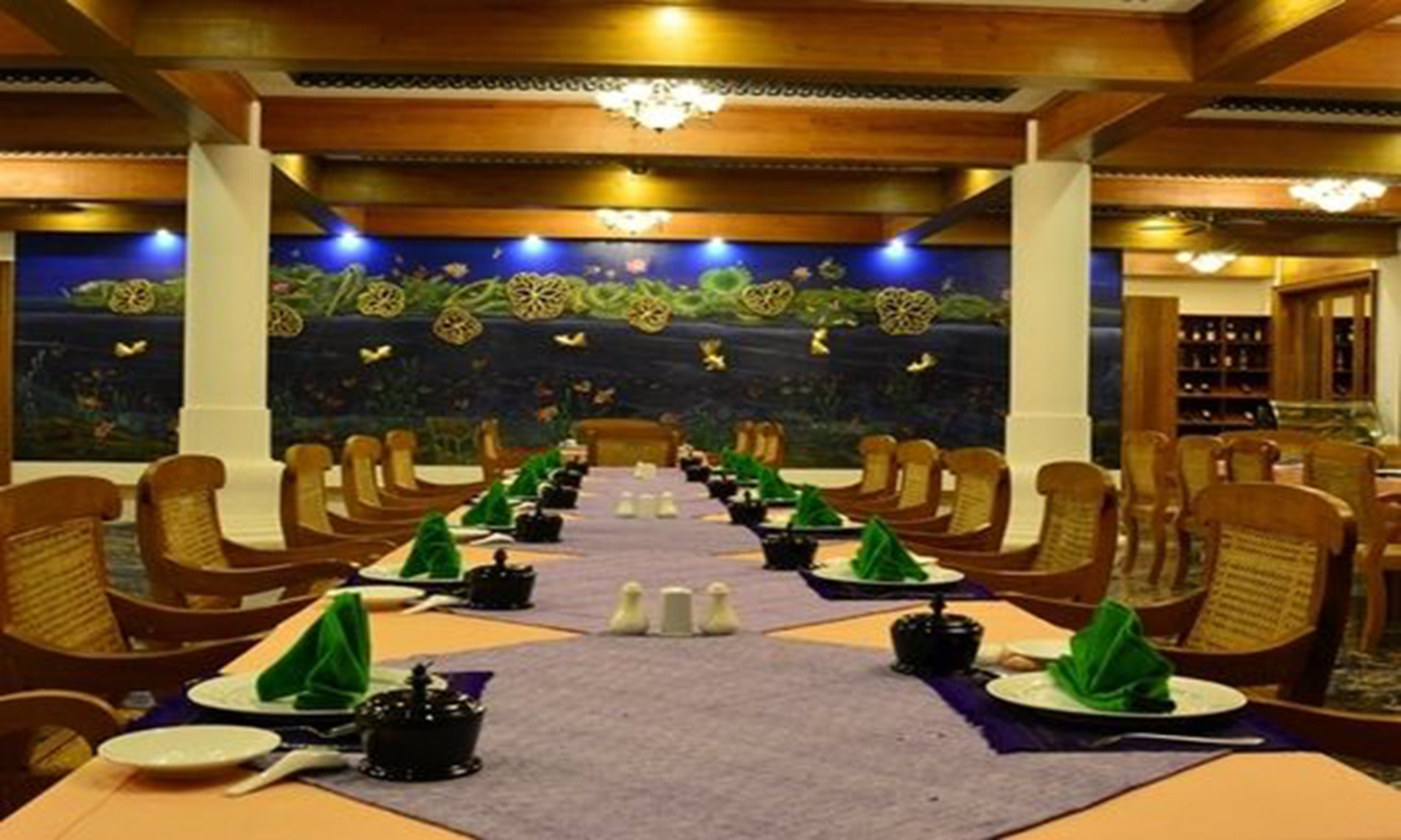A restaurant with a long table set for a meal, surrounded by wooden chairs.