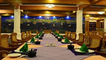 A restaurant with a long table set for a meal, surrounded by wooden chairs.