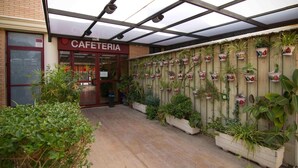 Una cafetería con cerramiento de madera y plantas en macetas.
