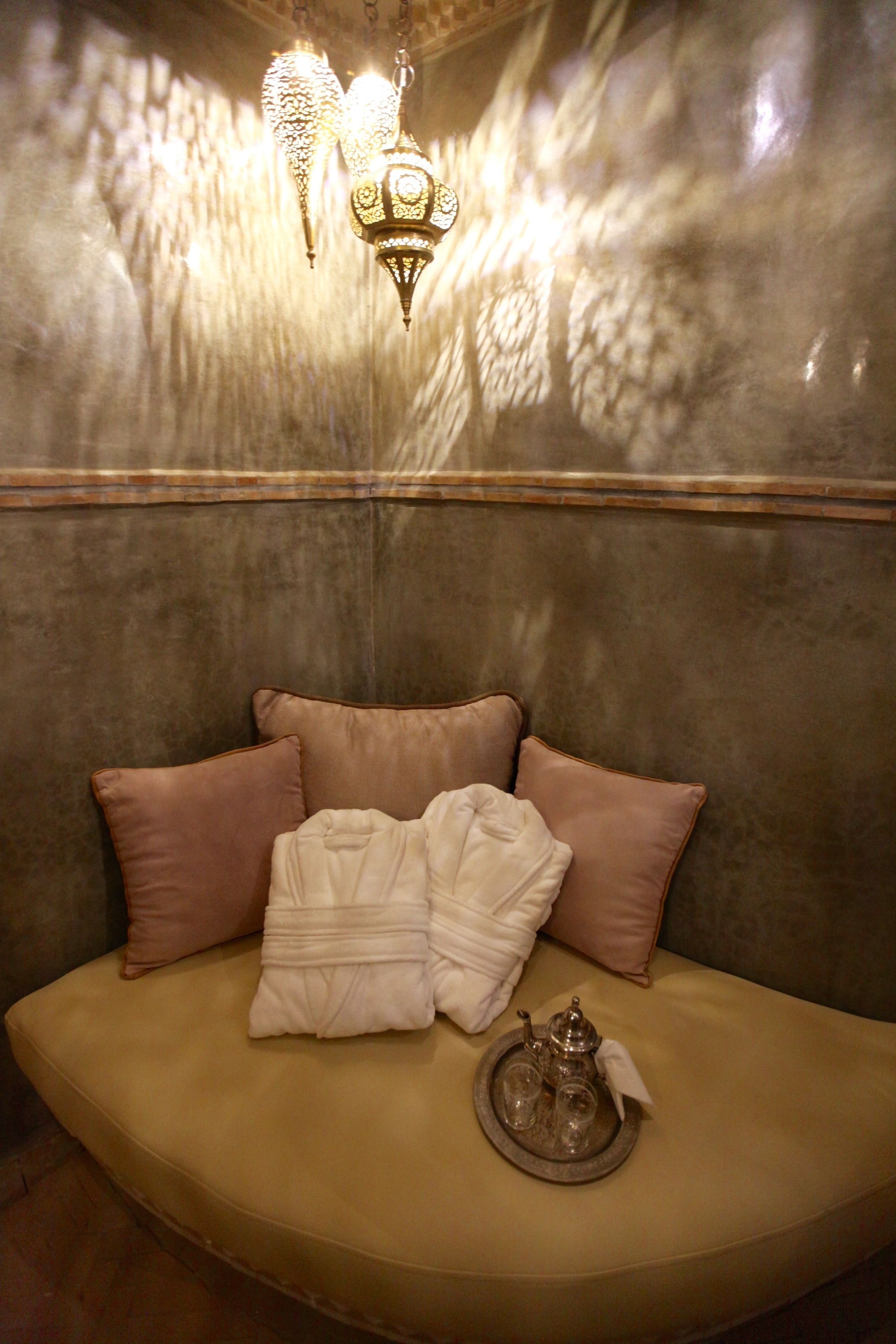 A seating area with a cushioned bench, pillows, and a tray with a teapot and cups.