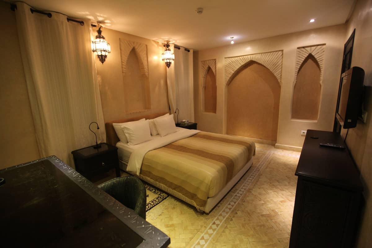 A hotel room with a large bed, a desk, and a TV.