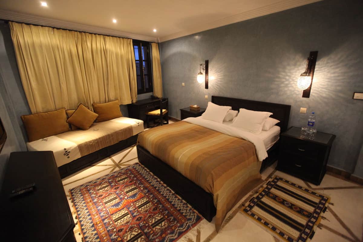 A hotel room with a large bed, a sofa, a desk, and a nightstand.