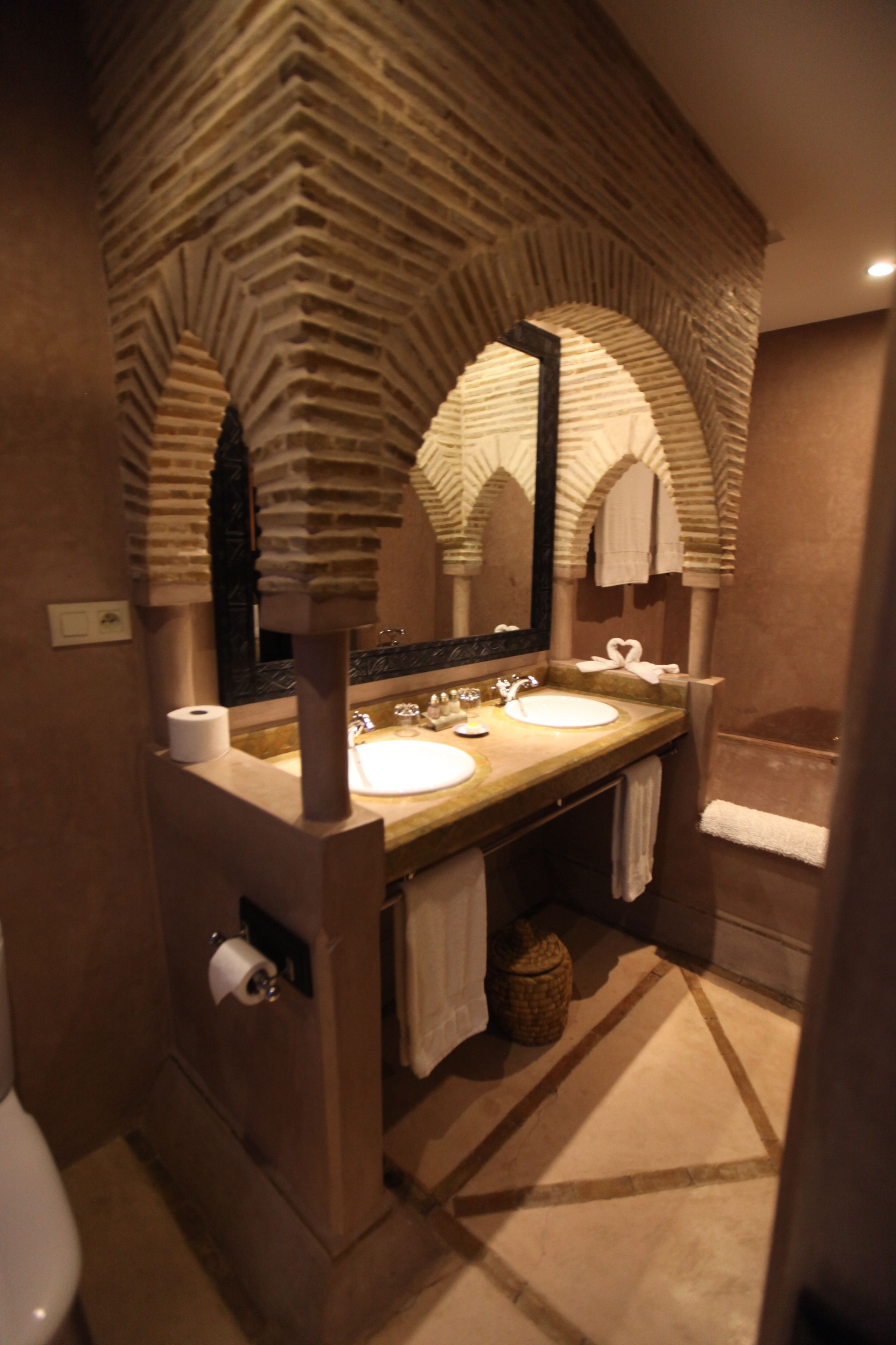 Un baño con diseño de arco de piedra, un lavamanos, un espejo y una bañera.