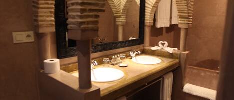 Un baño con diseño de arco de piedra, un lavamanos, un espejo y una bañera.