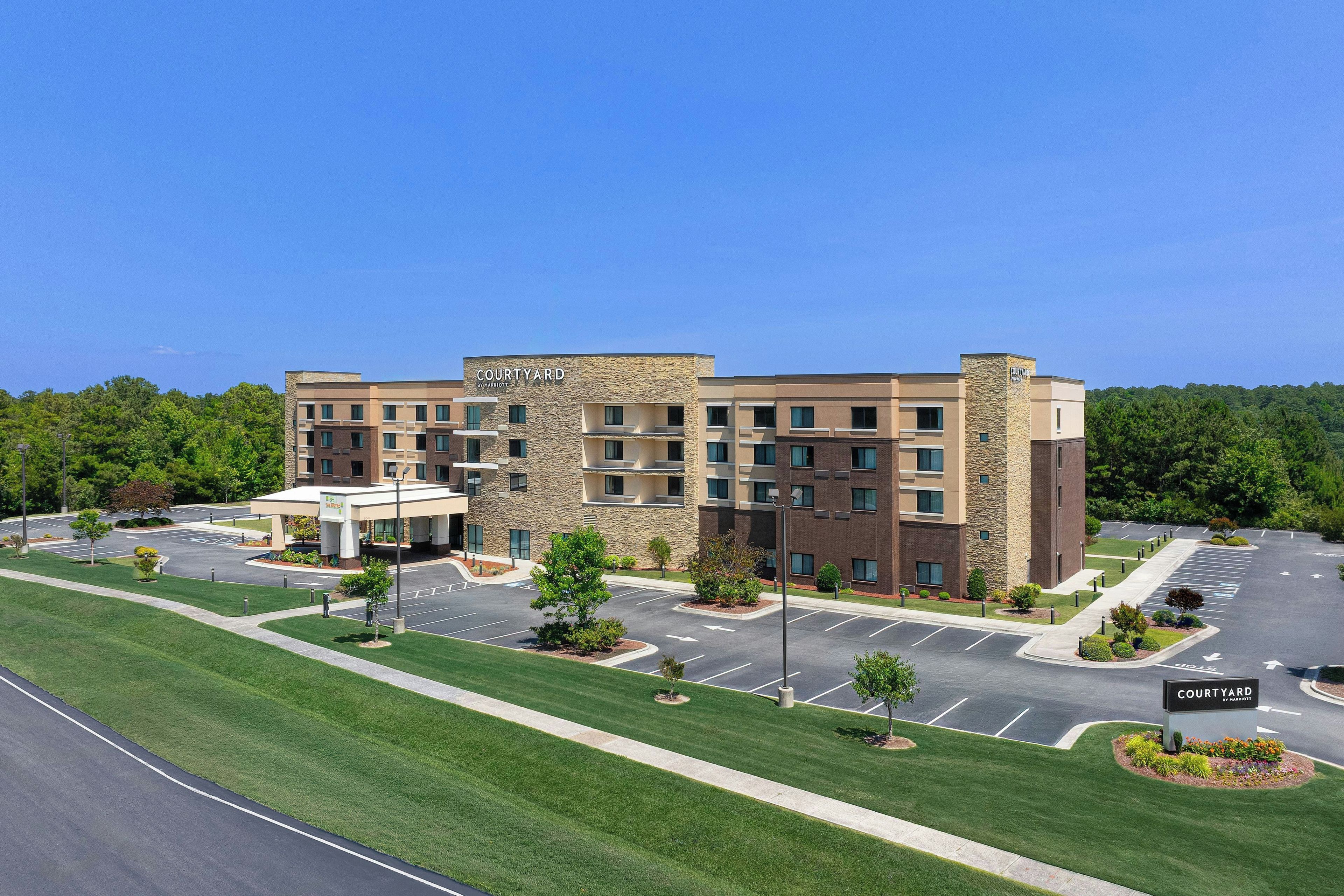 A Courtyard by Marriott hotel with a parking lot and a well-maintained lawn.