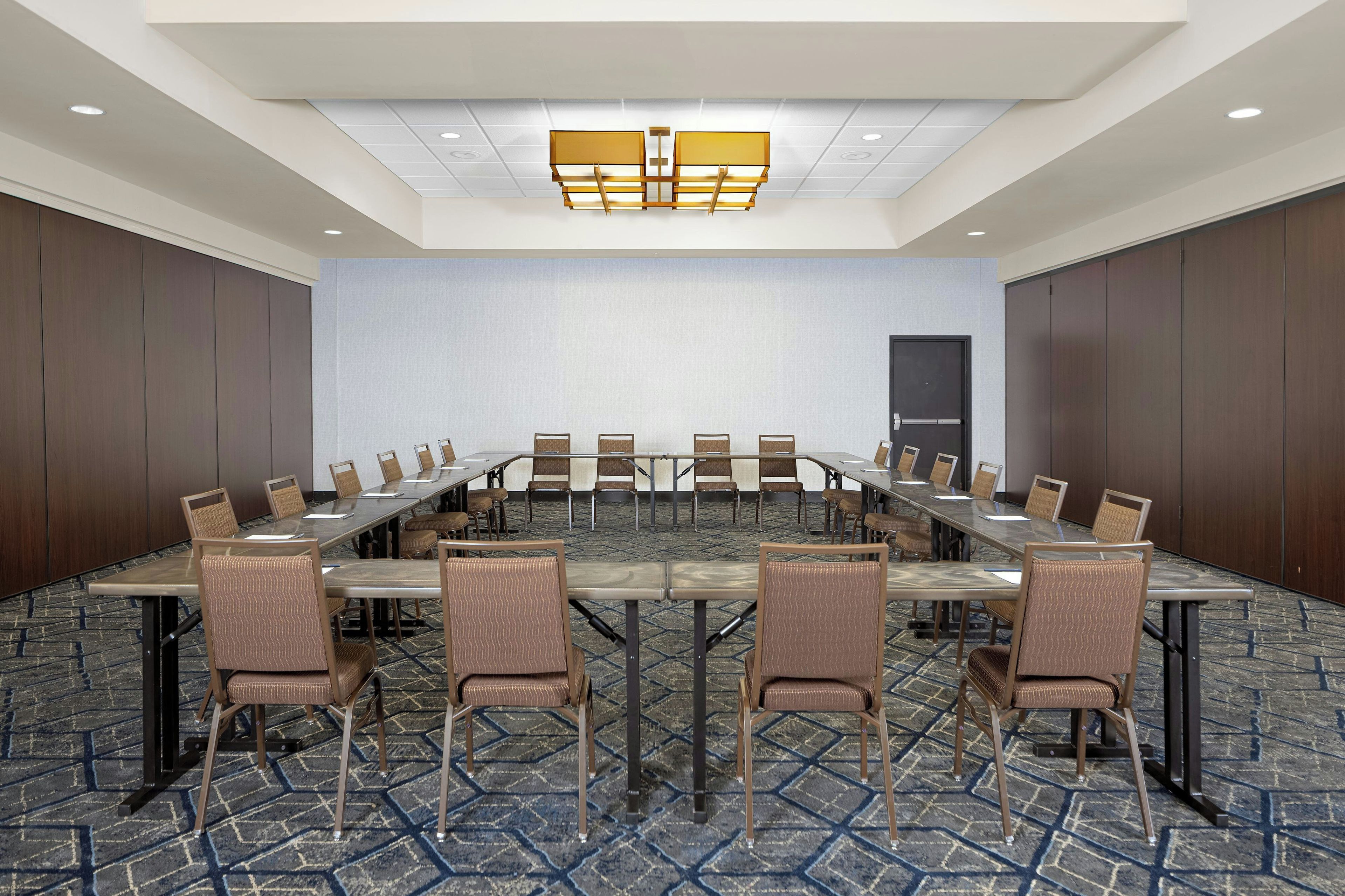 A conference room with a long table, chairs, and a patterned carpet.