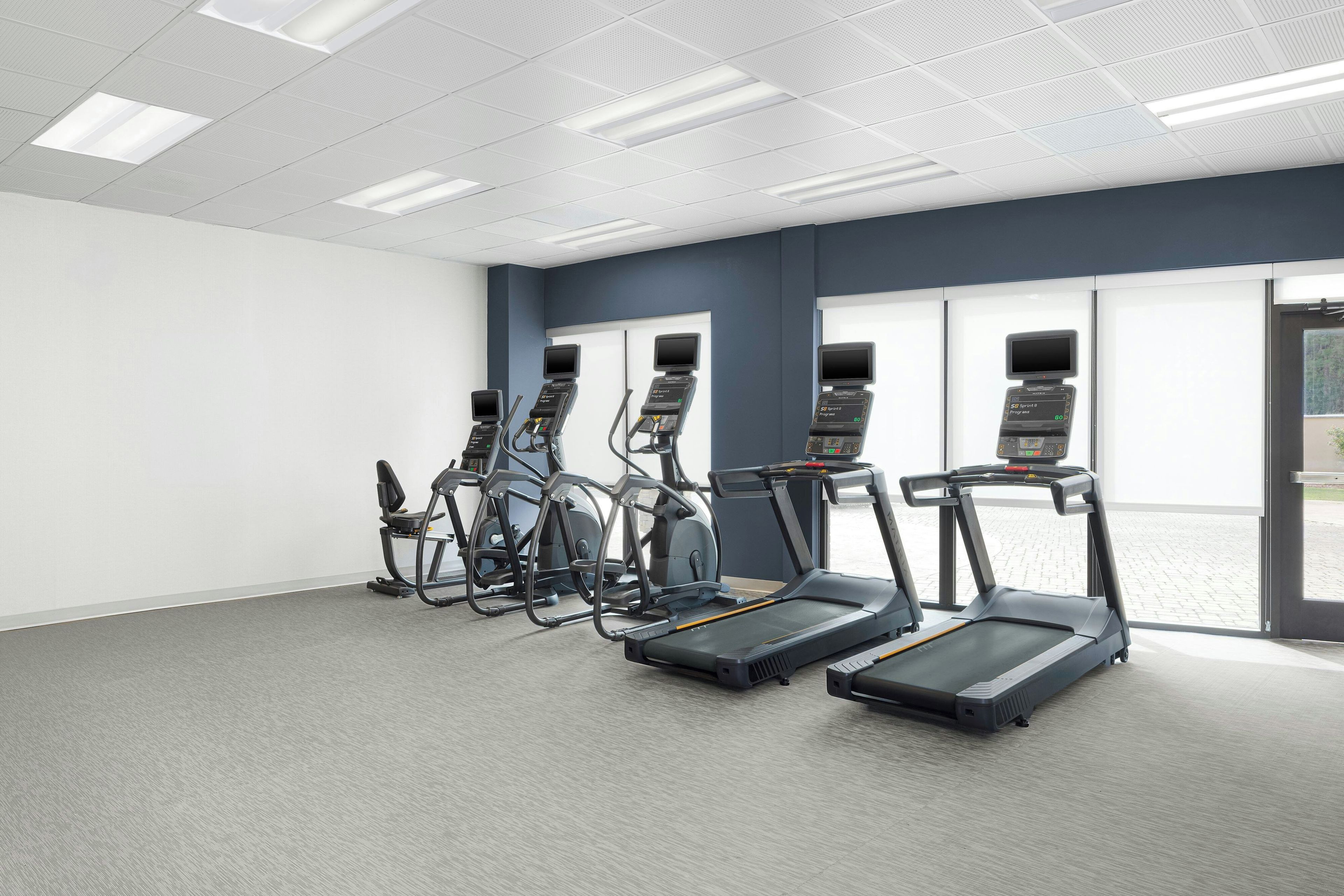 A fitness room with treadmills, elliptical machines, and stationary bikes.