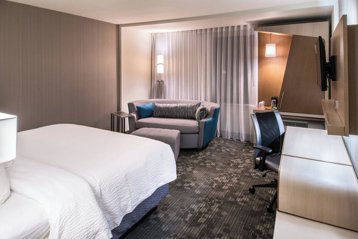 Une chambre d’hôtel avec un grand lit, un canapé, un bureau et une chaise.