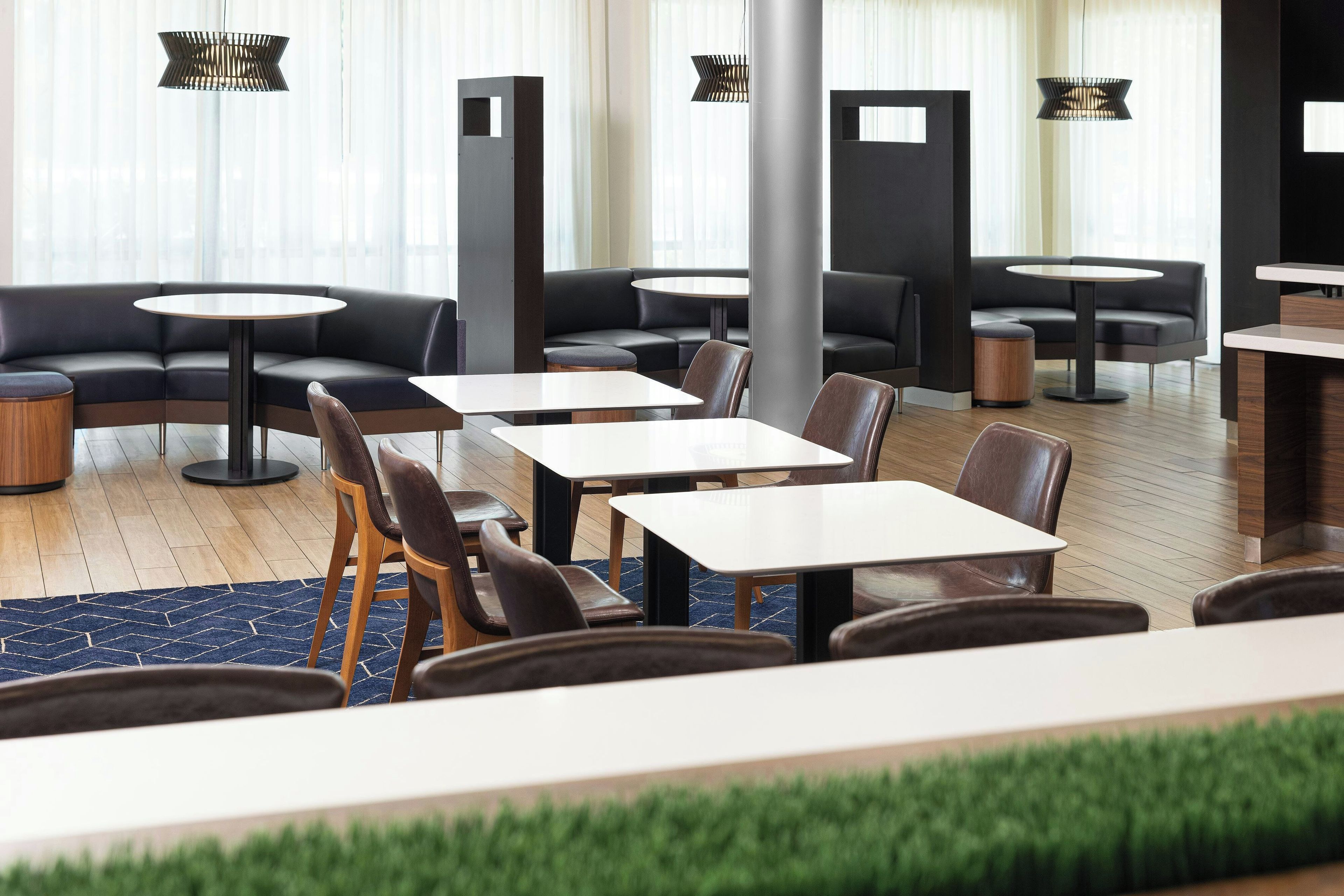 A modern hotel lobby with leather seating, round tables, and pendant lighting.