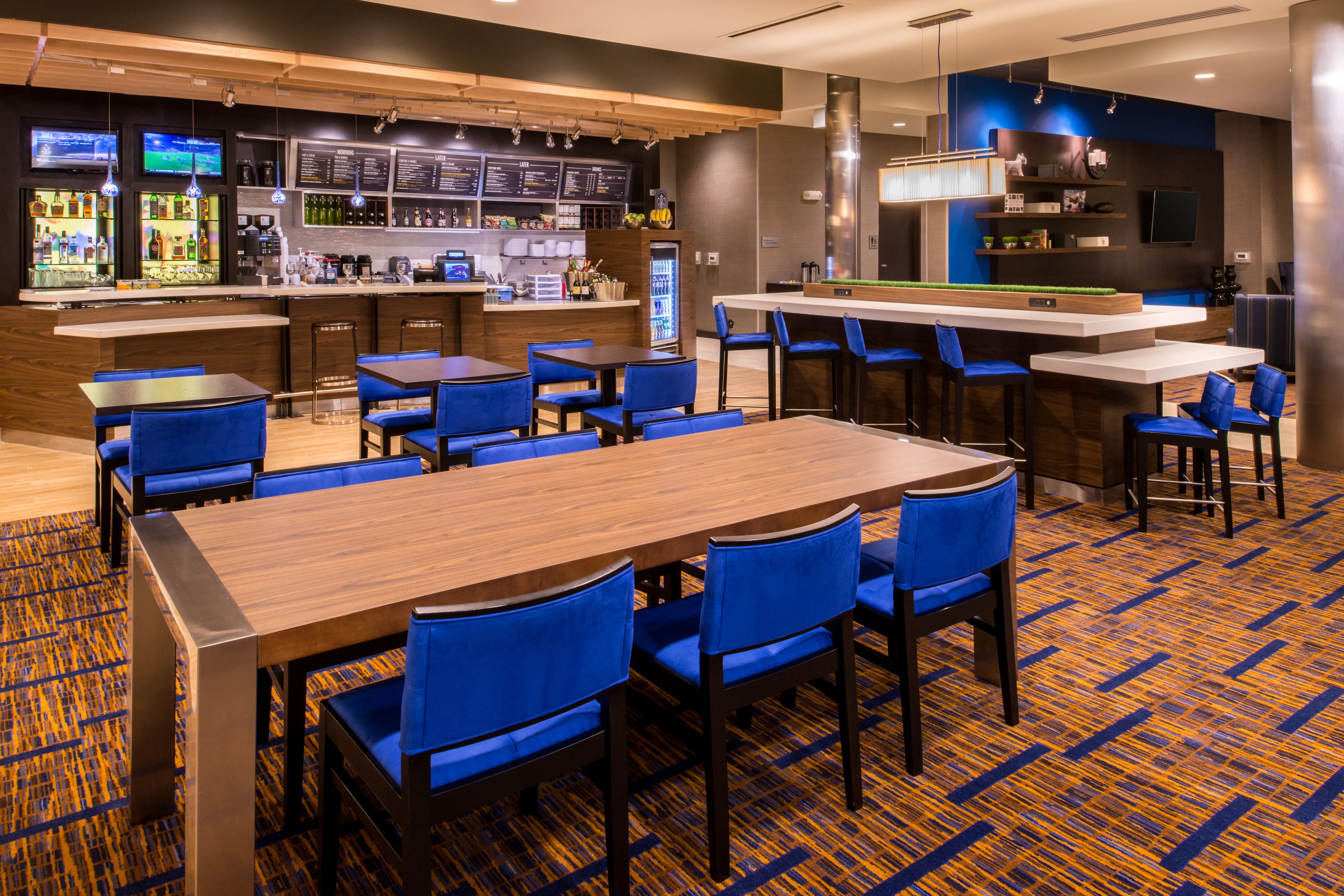 A modern bar area with multiple seating options, including bar stools and tables, and a variety of beverages and snacks available.