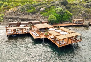 Una estructura de madera flotante con varias habitaciones, cada una con balcón y zona de estar, con vistas a un cuerpo de agua.