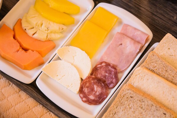 Un plato con varios quesos, embutidos y rebanadas de pan.