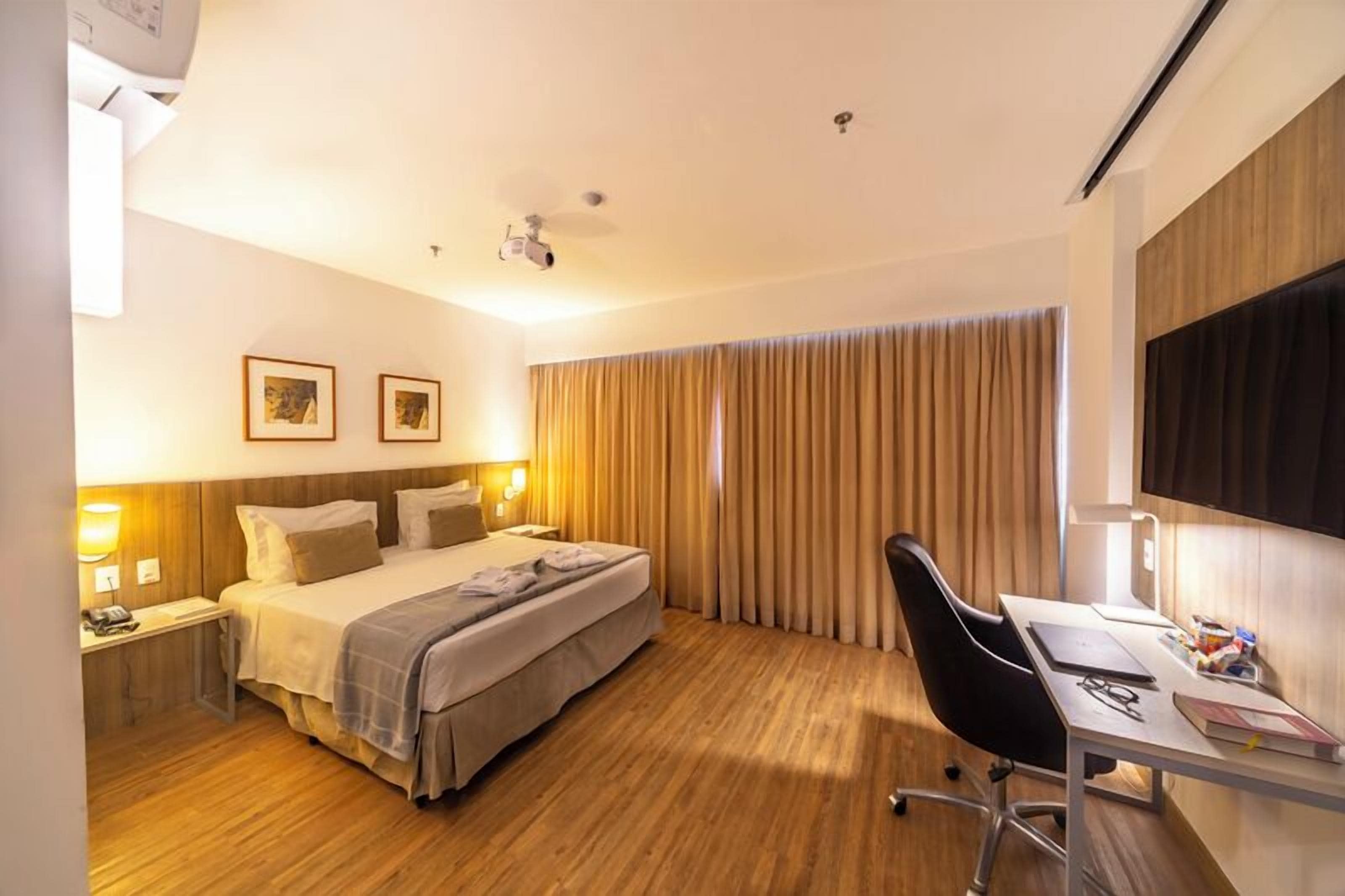 Una habitación de hotel con cama, mesitas de noche, escritorio y una silla.