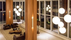 Un vestíbulo moderno con sofás de cuero, una columna de madera e iluminación colgante.