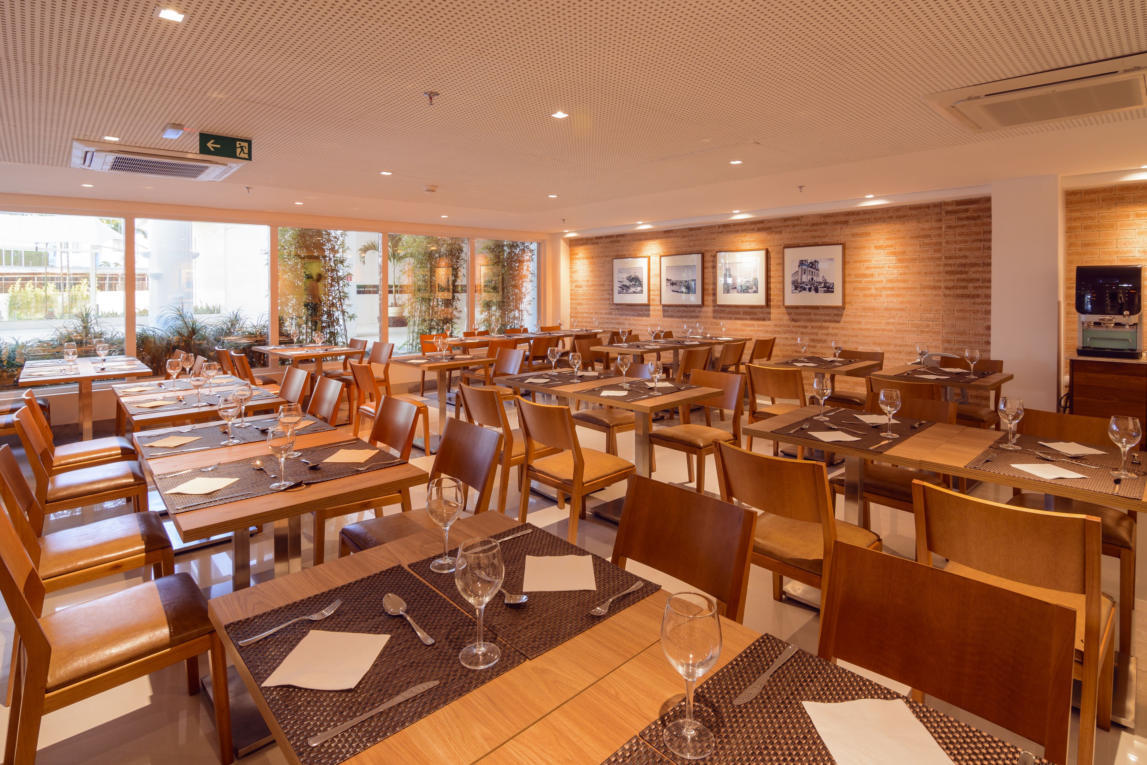A restaurant with multiple tables and chairs, arranged in a spacious layout with large windows allowing natural light.
