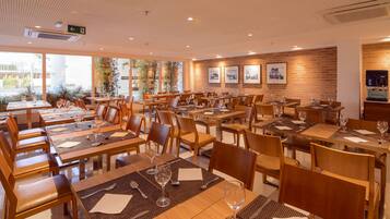 A restaurant with multiple tables and chairs, arranged in a spacious layout with large windows allowing natural light.