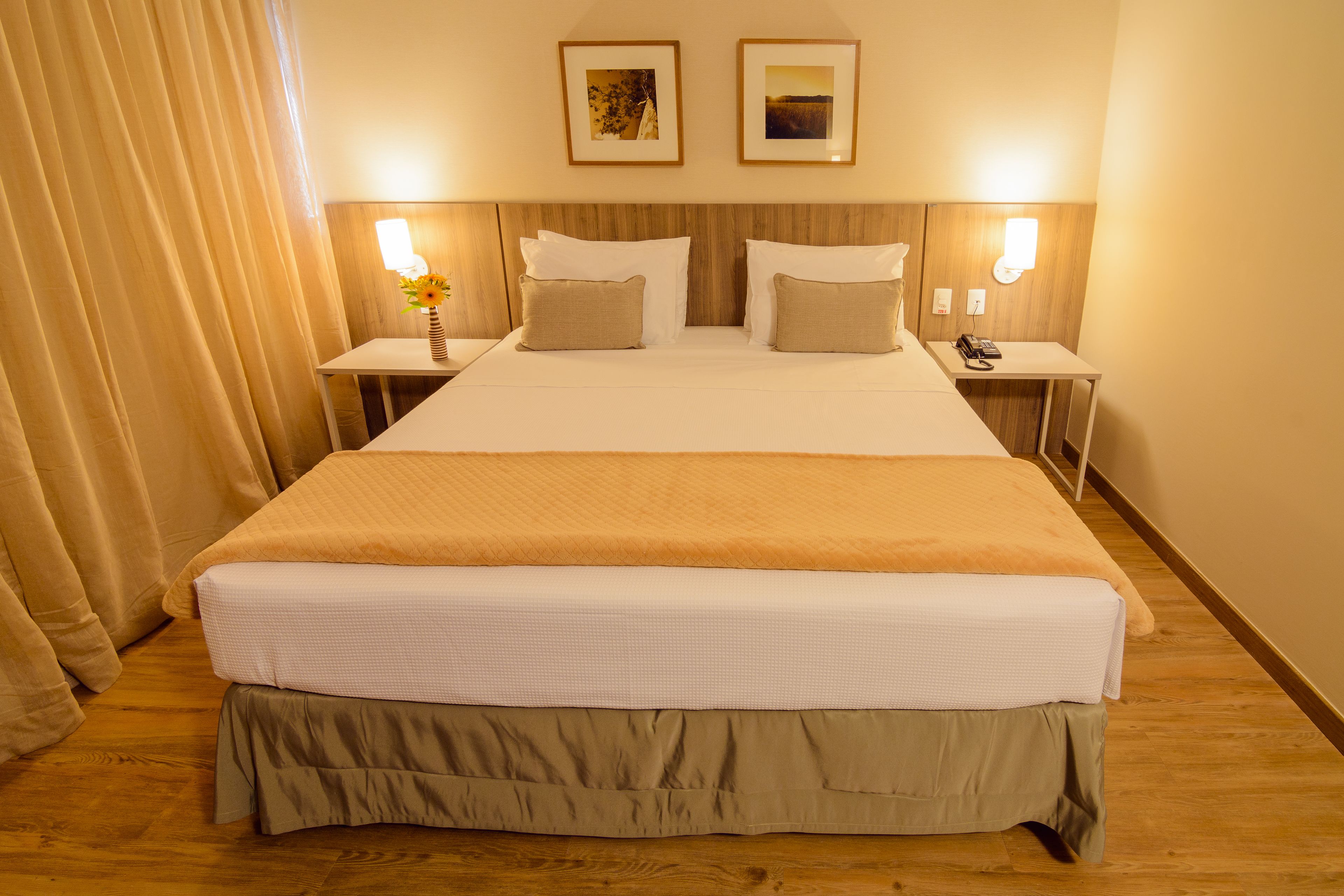 Ein Hotelzimmer mit einem großen Bett, zwei Nachttischen, einer Ablagefläche und einer Lampe.