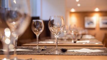 Una mesa de comedor con copas de vino y cubiertos, sobre un mantel individual texturizado.