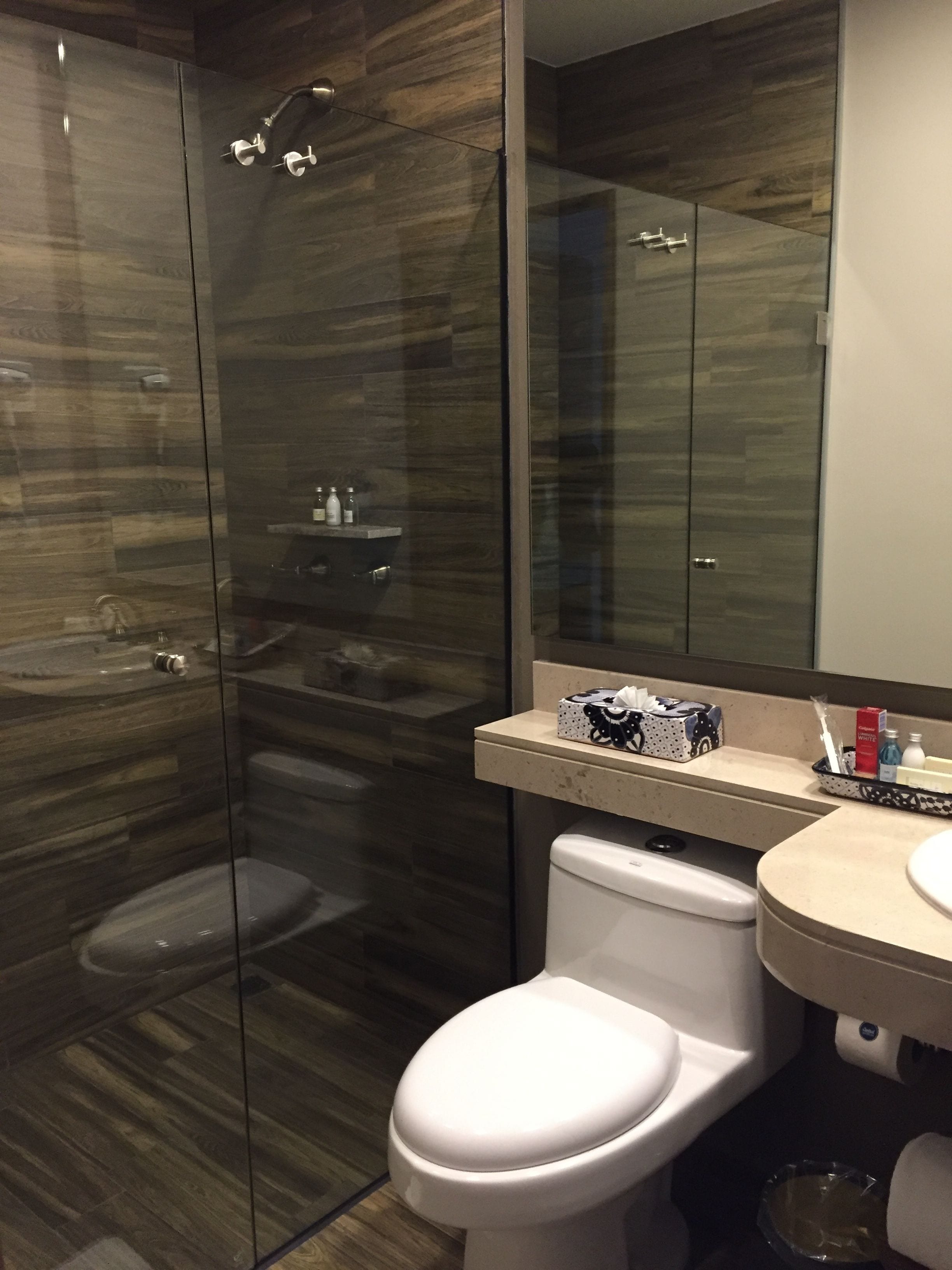 Une salle de bain moderne avec une douche à parois de verre, des toilettes blanches et un meuble-lavabo avec des articles de toilette.