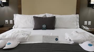Ein Hotelzimmer mit einem großen Bett, weißen Leinentüchern, einem dunklen Kopfteil und einem Schild auf dem Bett.