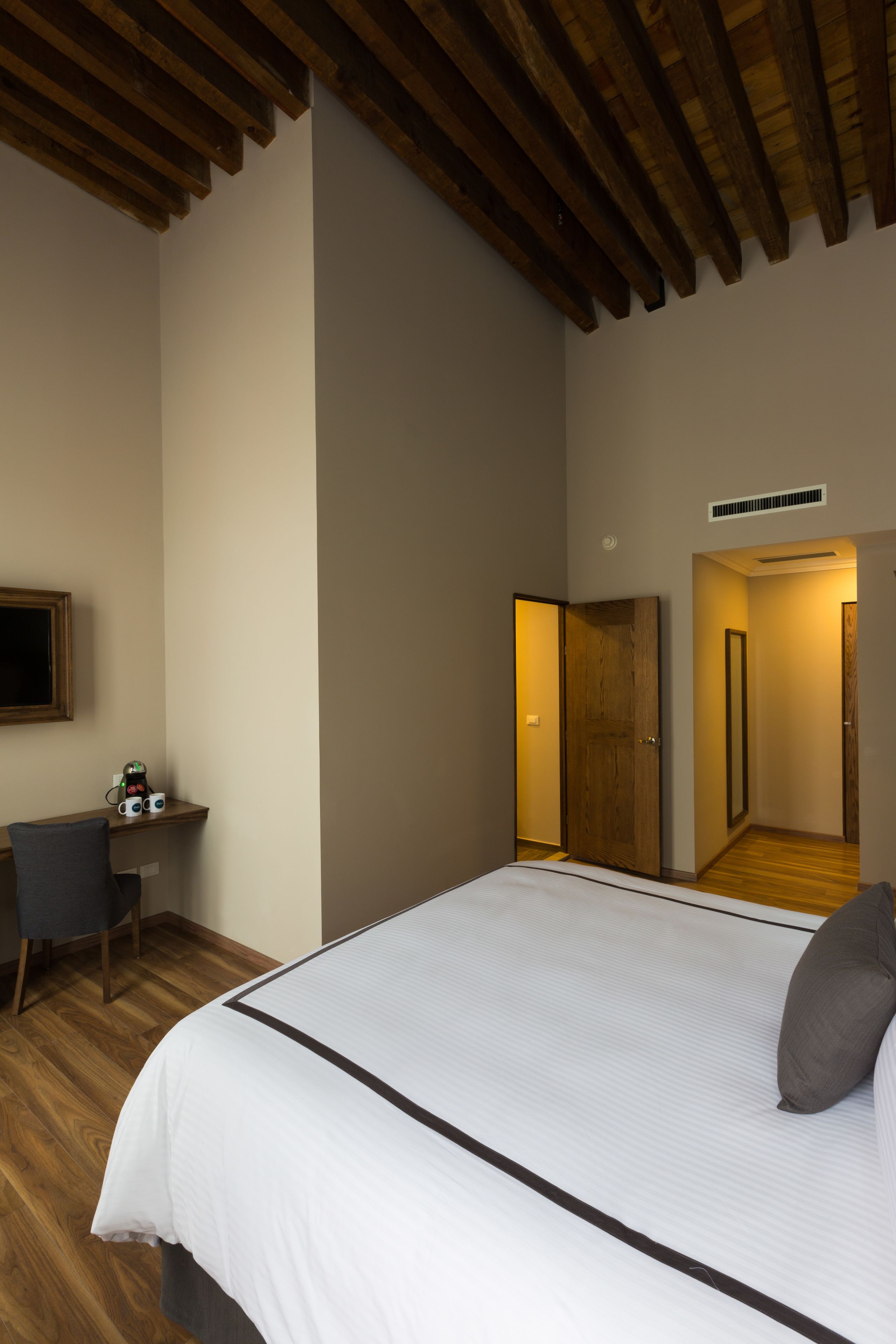 A bedroom with a large bed, a desk, and a mirror.