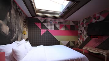 A hotel room with a bed, a bench, a TV, and a mural on the wall.