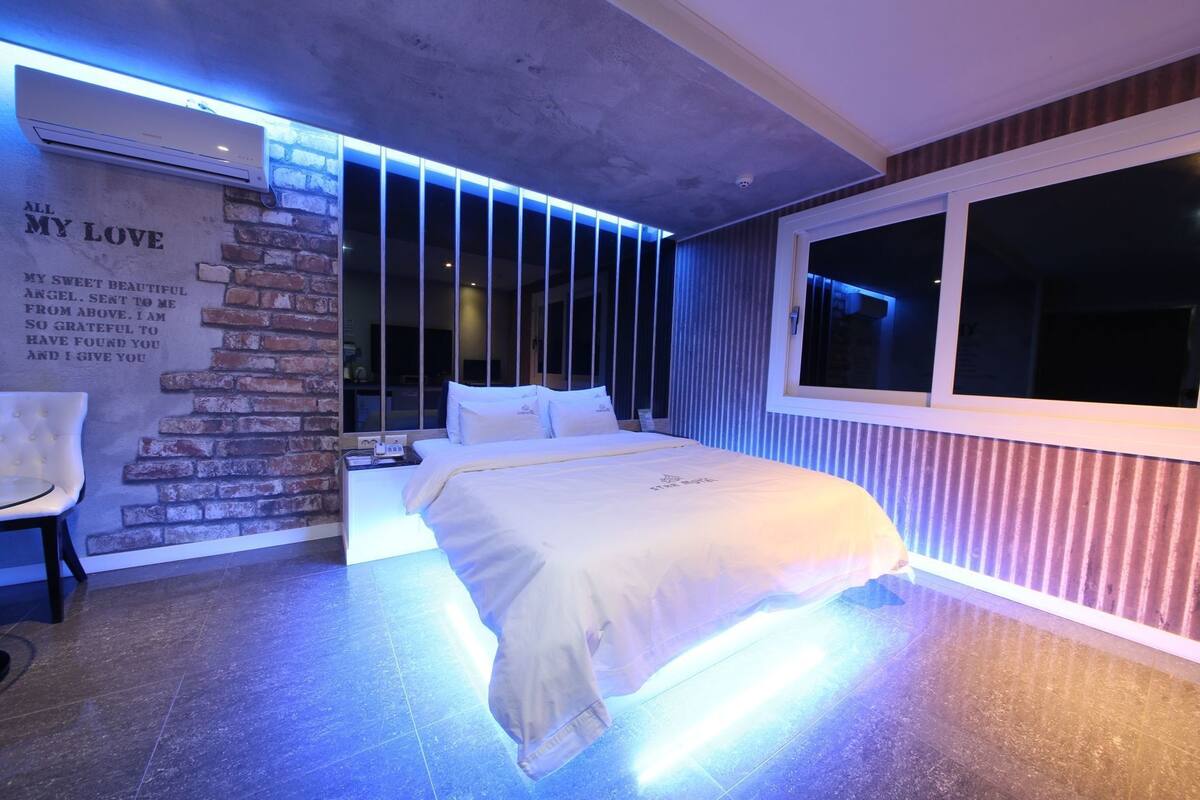 Un dormitorio moderno con cama, una silla, una pared con una cita y una ventana.