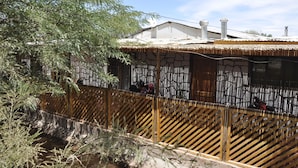 A traditional house with a tiled roof, a stone wall, and a wooden fence. - Residencial Chiloe (San Pedro de Atacama)