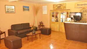 A reception area with a wooden desk, a sofa, and a coffee table. - Residencial Chiloe (San Pedro de Atacama)