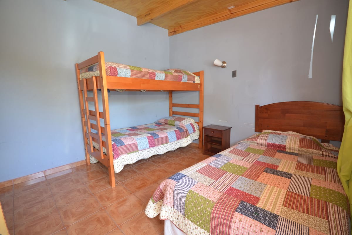 A bunk bed room with a wooden headboard, a nightstand, and a quilted bedspread.