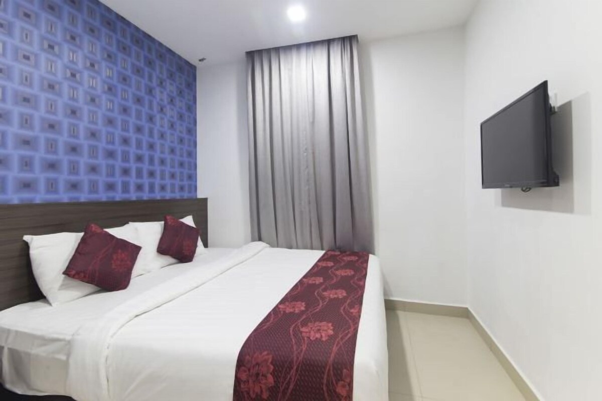 A hotel room with a bed, a TV mounted on the wall, and a patterned wall.