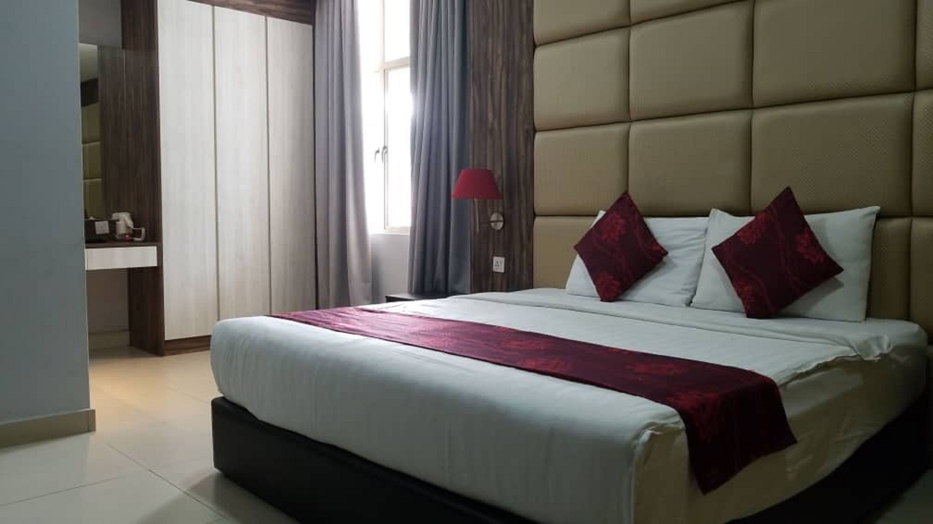 Una habitación de hotel con una cama grande, una mesita de noche, una lámpara y un armario.