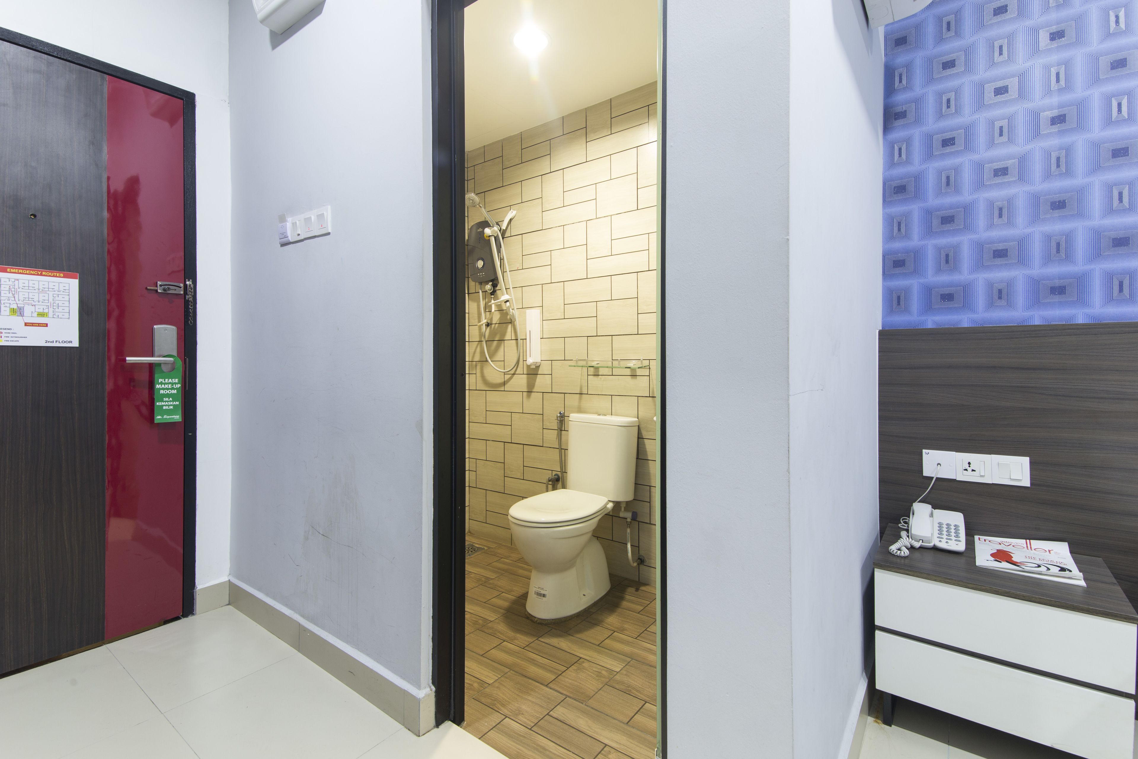 Un bagno con il water, doccia e un comodino con un telefono e una rivista.