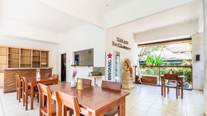 A spacious dining area with wooden furniture, a Bintang sign, and a statue. - Balian Paradise Hotel (Selemadeg)