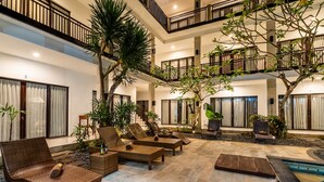 A multi-level indoor courtyard with wicker furniture, potted plants, and a pool area. - Balian Paradise Hotel (Selemadeg)