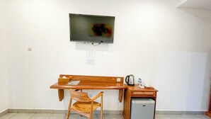 A room with a wooden desk, a chair, a television mounted on the wall, and a small refrigerator. - Balian Paradise Hotel (Selemadeg)