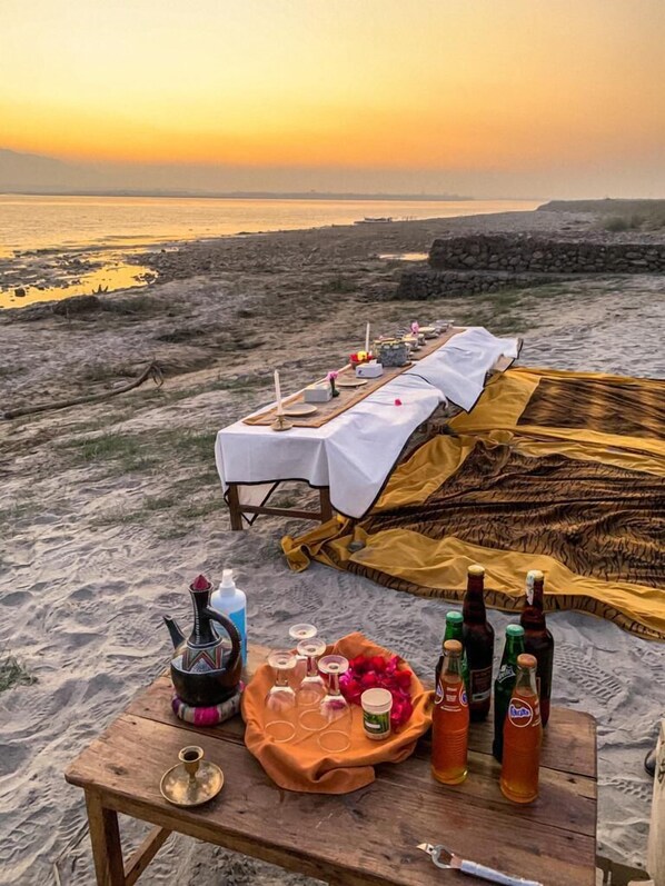 En picknickplats på stranden med ett bord, filtar och flaskor.
