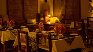 A dining area with tables set for a meal, chairs, and a central table with a decorative centerpiece.