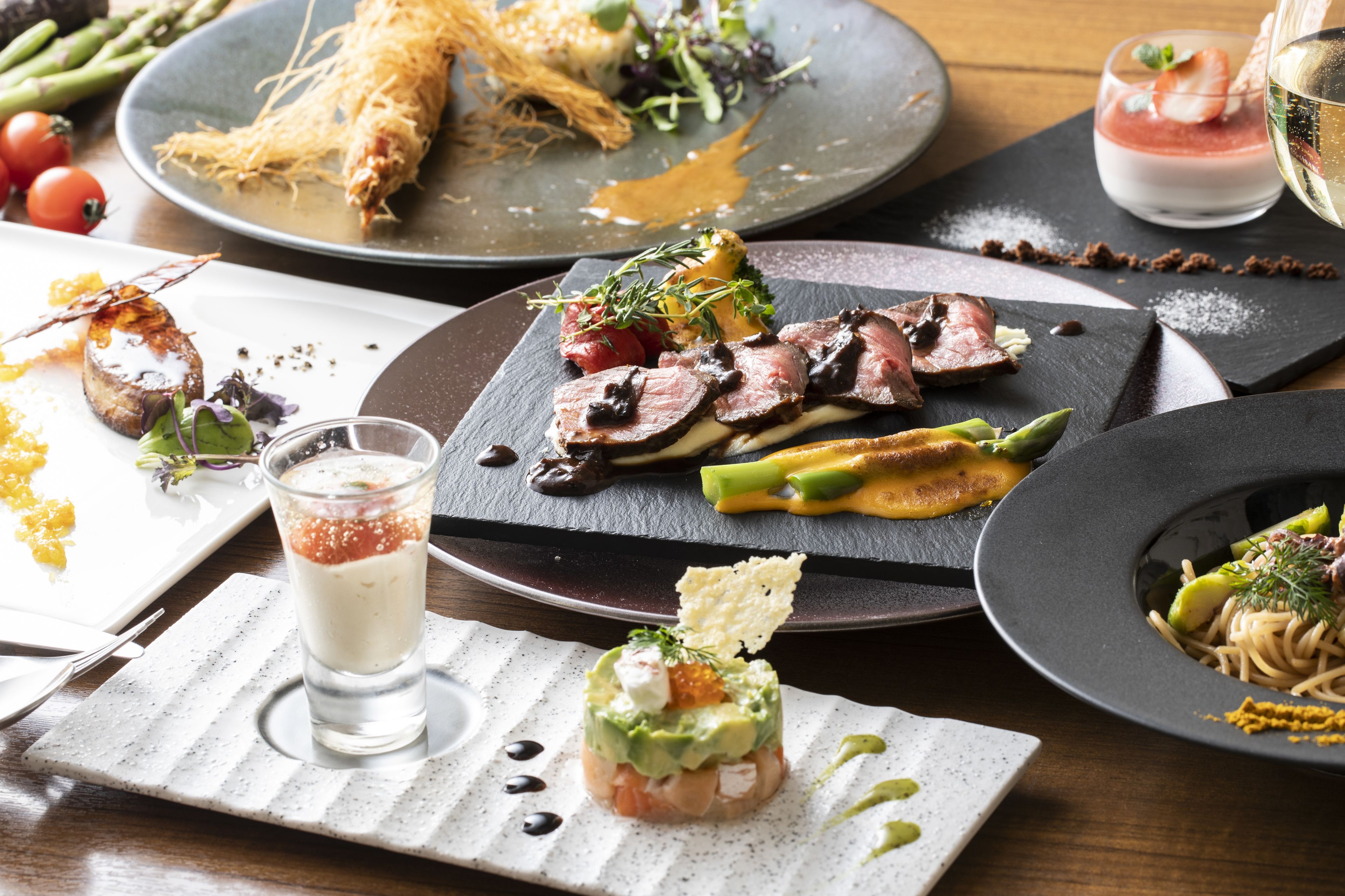 A variety of dishes on a dining table, including seafood, vegetables, and a dessert.