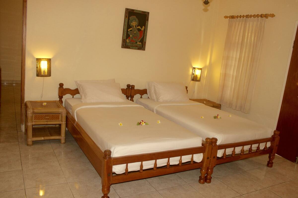 A double bed with white linens, two bedside tables with lamps, and a wall-mounted painting.