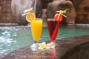 Two drinks with fruit garnishes on a wooden ledge by a pool. - Chonos Hotel Lovina (Buleleng)