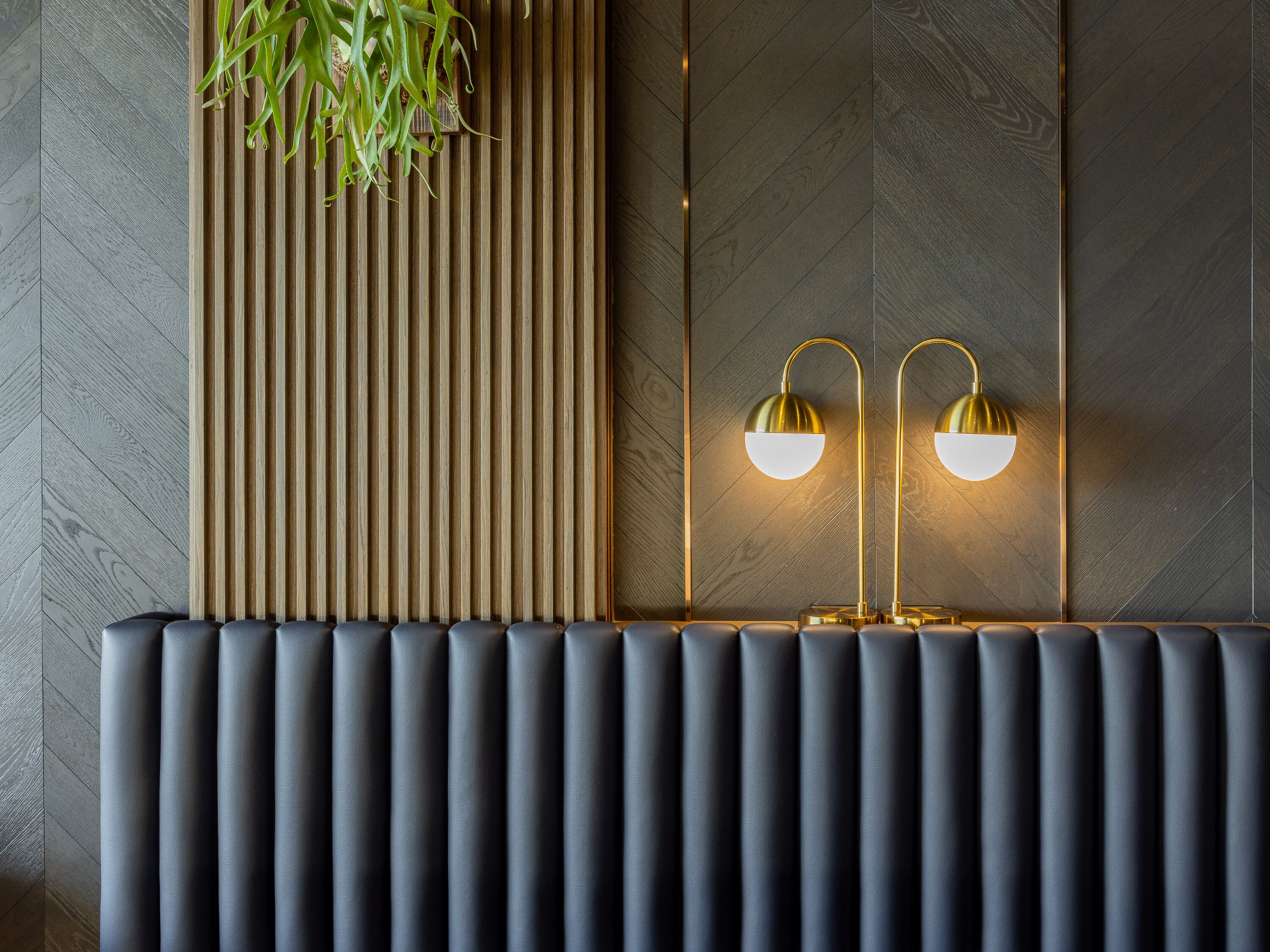 A modern interior with a wooden slat wall, a radiator, and two wall-mounted lamps.