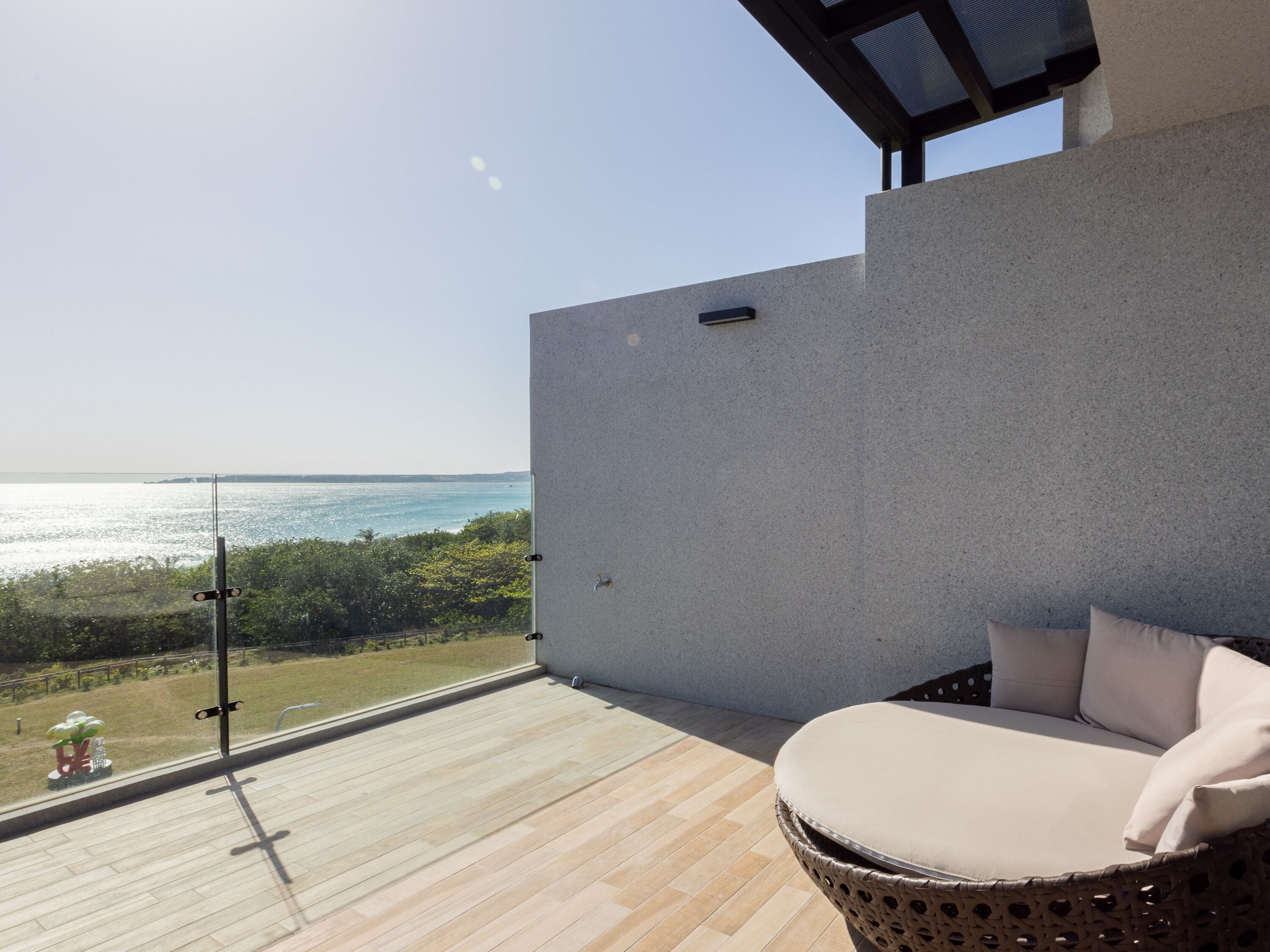 A balcony with a wicker chair and a view of the sea.