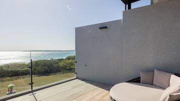 A balcony with a wicker chair and a view of the sea.