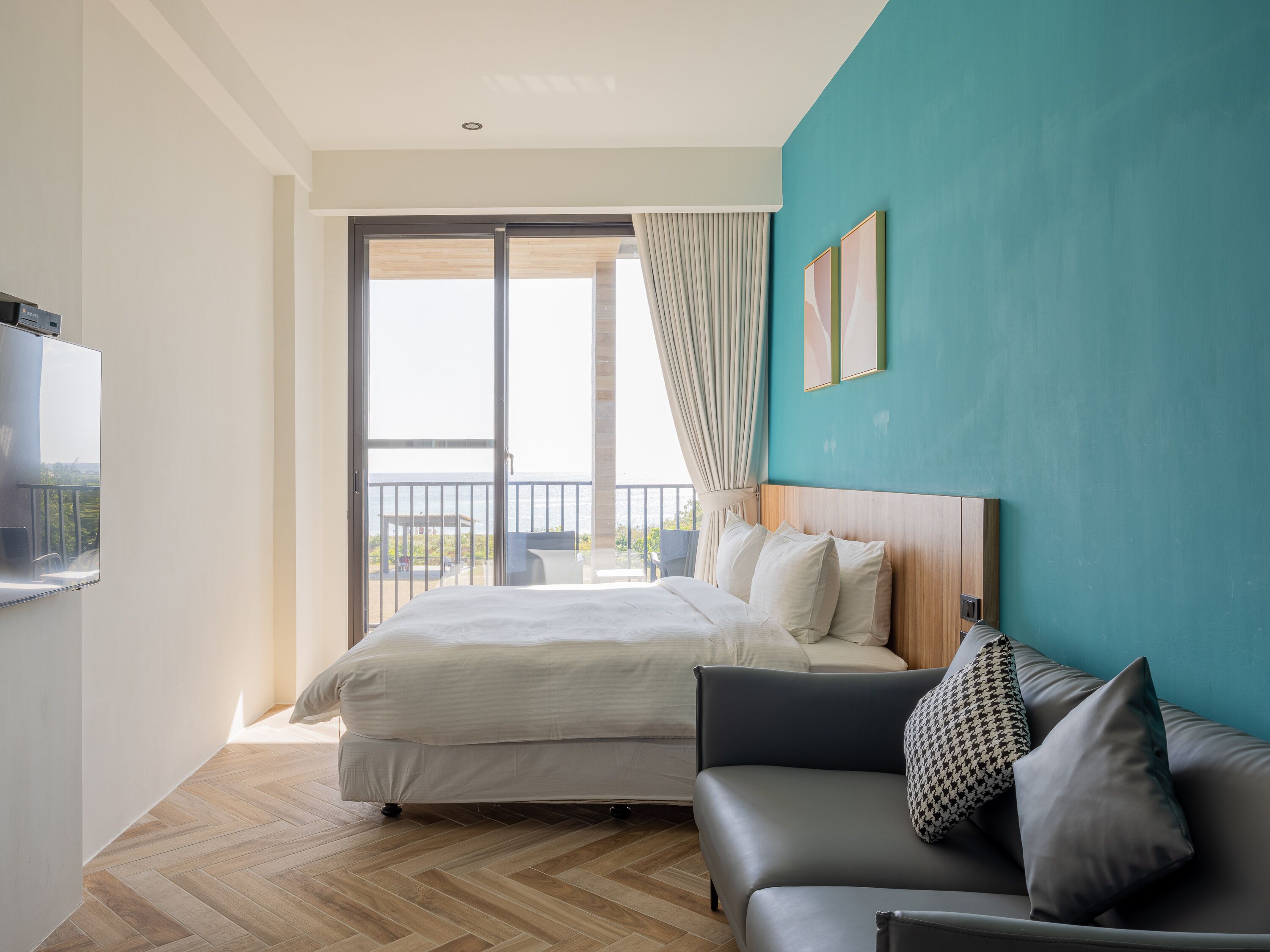 Una habitación de hotel con cama, sofá, televisión y balcón con vistas.