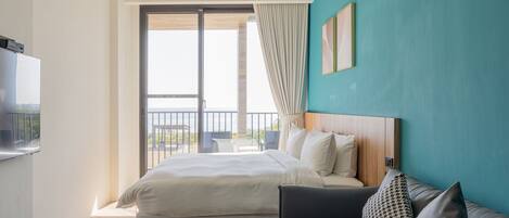 Una habitación de hotel con cama, sofá, televisión y balcón con vistas.