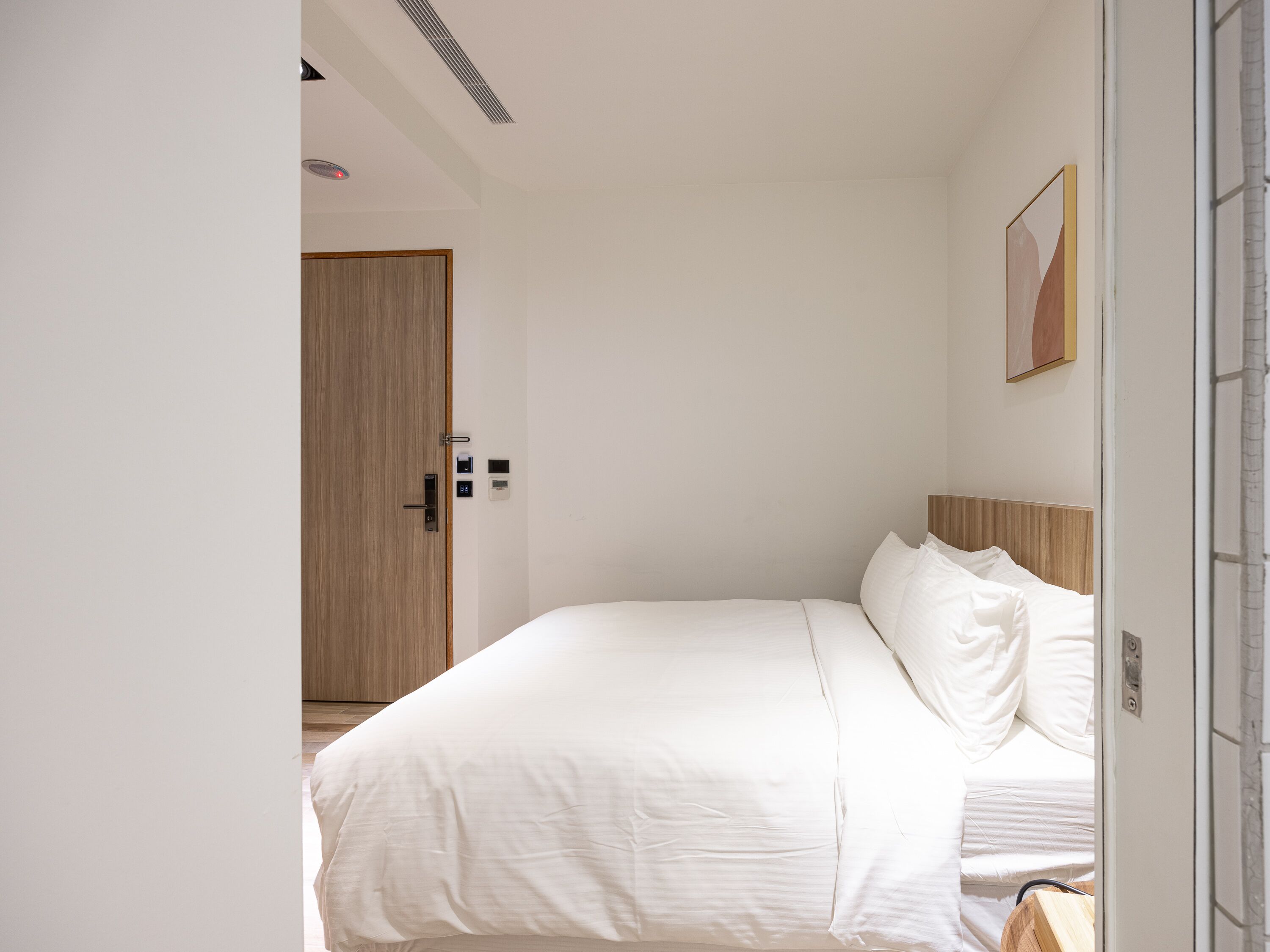 Un dormitorio con cama, una puerta de madera y un aplique en la pared.