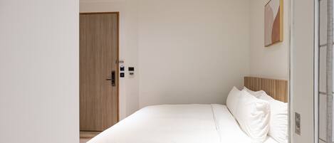 Un dormitorio con cama, una puerta de madera y un aplique en la pared.